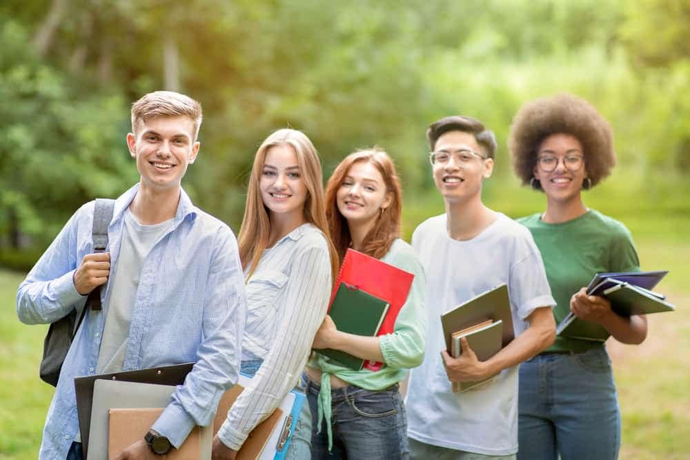 A group of students participating in a Grant Program standing together in a park.