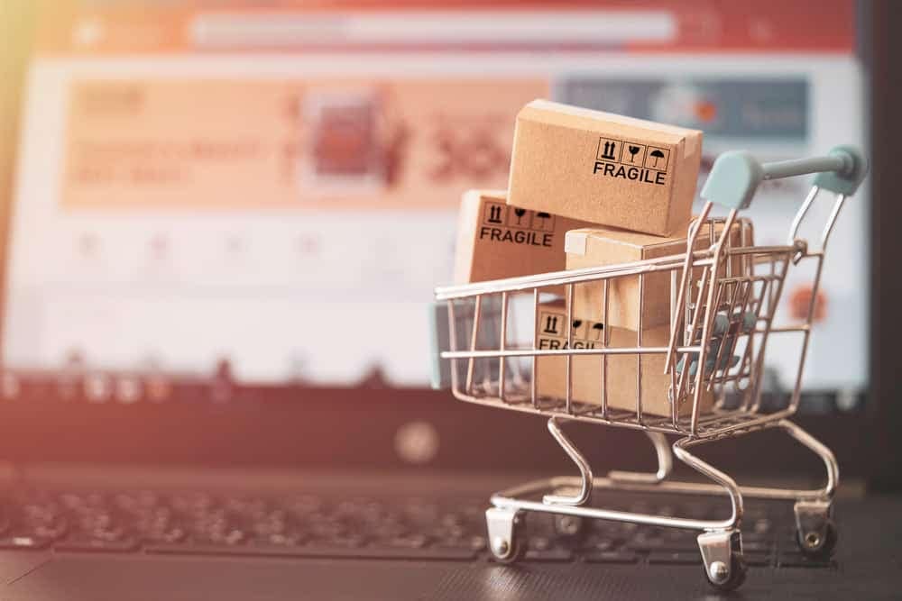 A shopping cart with boxes sitting on top of a laptop at the Aftermarket Conference.