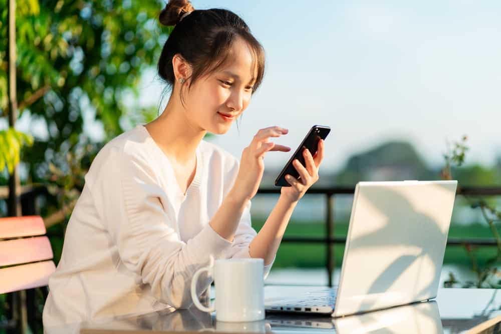 A woman working on a laptop at an outdoor table at a campsite.