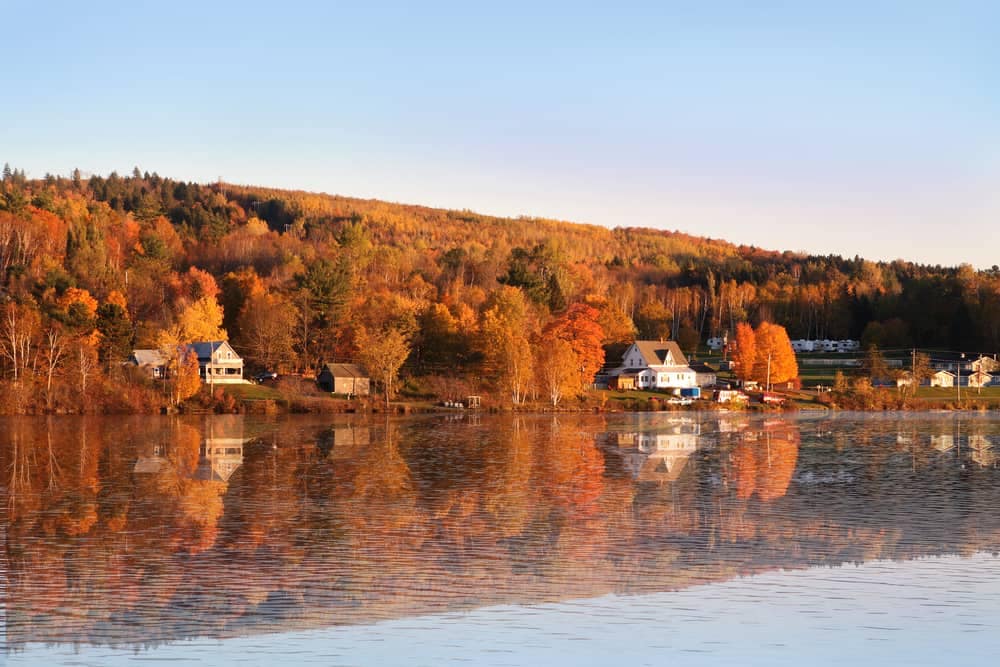 A high traffic lake in New Brunswick attracting tourism, with houses reflected in the water.