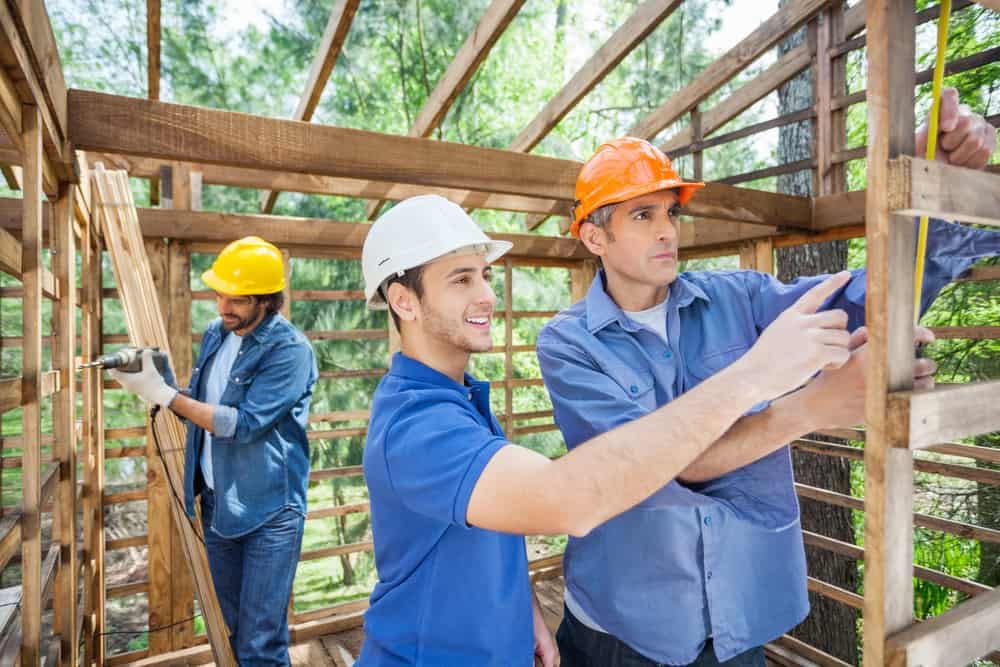 Three construction workers working on a wooden house proposal at Norfolk's 46-cabin Holiday Park.