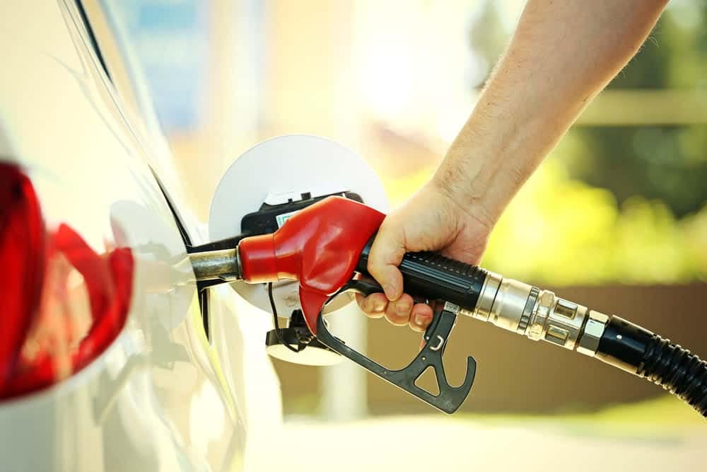 A driver relieving their wallet at the gas pump due to rising gas prices.
