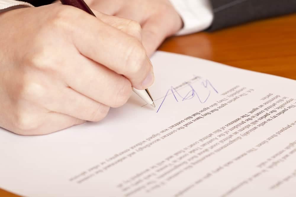 A person signing a document with a pen, in accordance with the law.