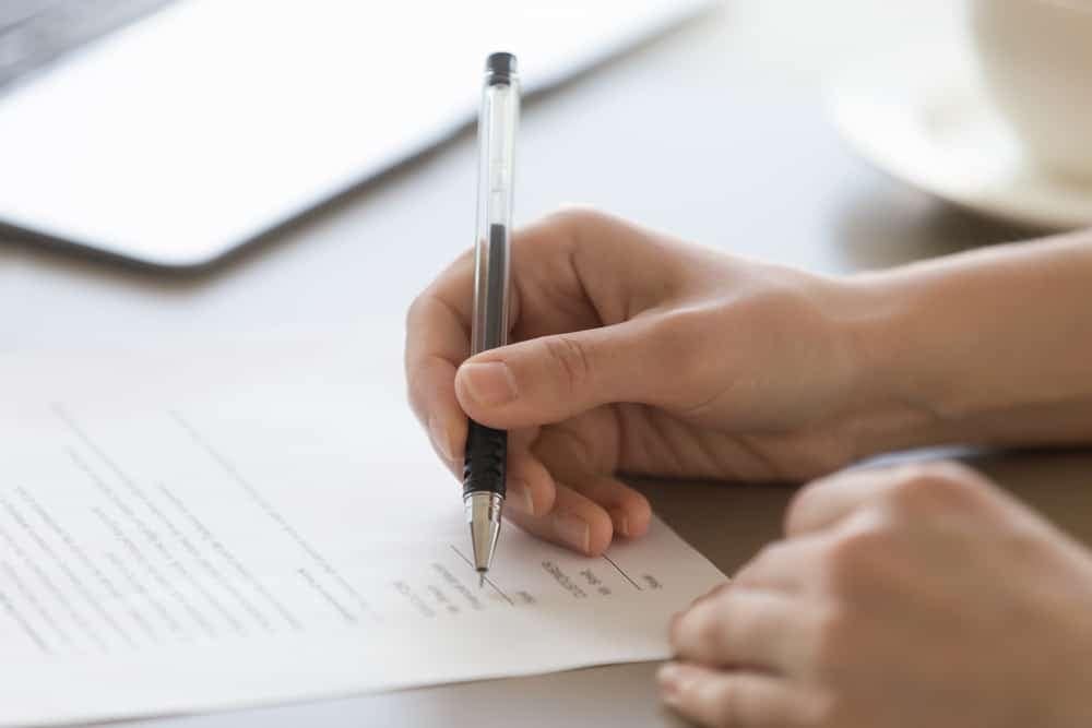 A person signing a document with a pen related to legislation for short-term let in Highland accommodation.