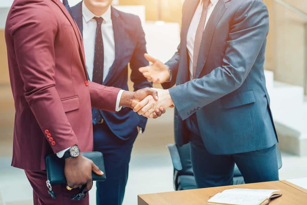 Three partners shaking hands in front of a desk at Bosque Ranch.
