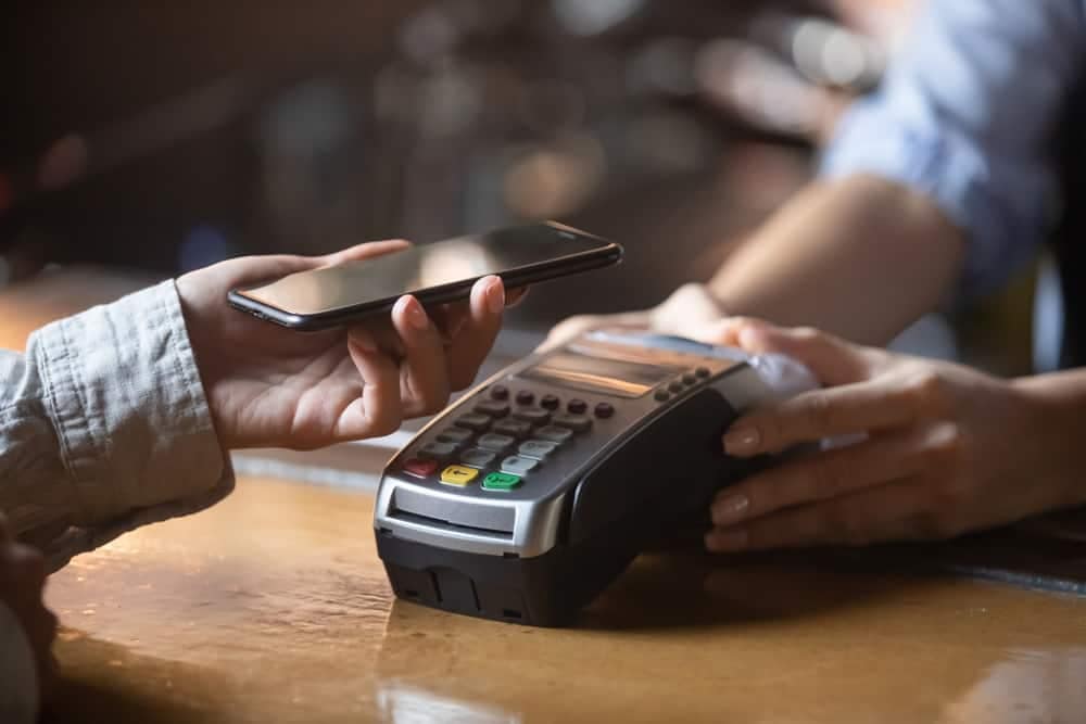 A person is using a smartphone to pay for a drink cashlessly at a bar.