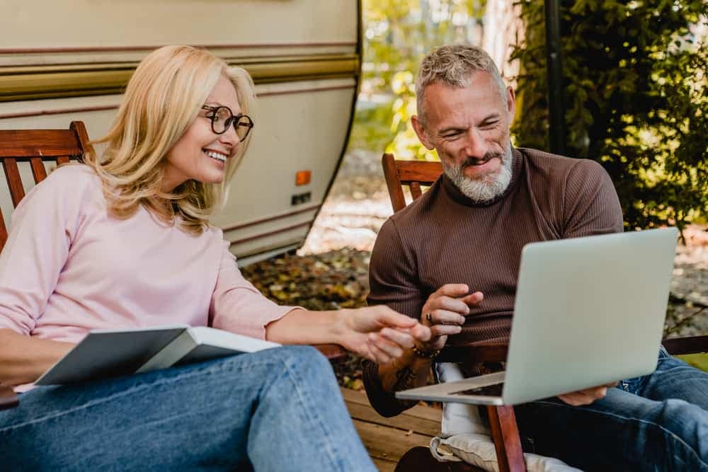 An older couple using a laptop in front of their RV, exploring the FinTech solutions offered by Octane Enters in the booming RV market.