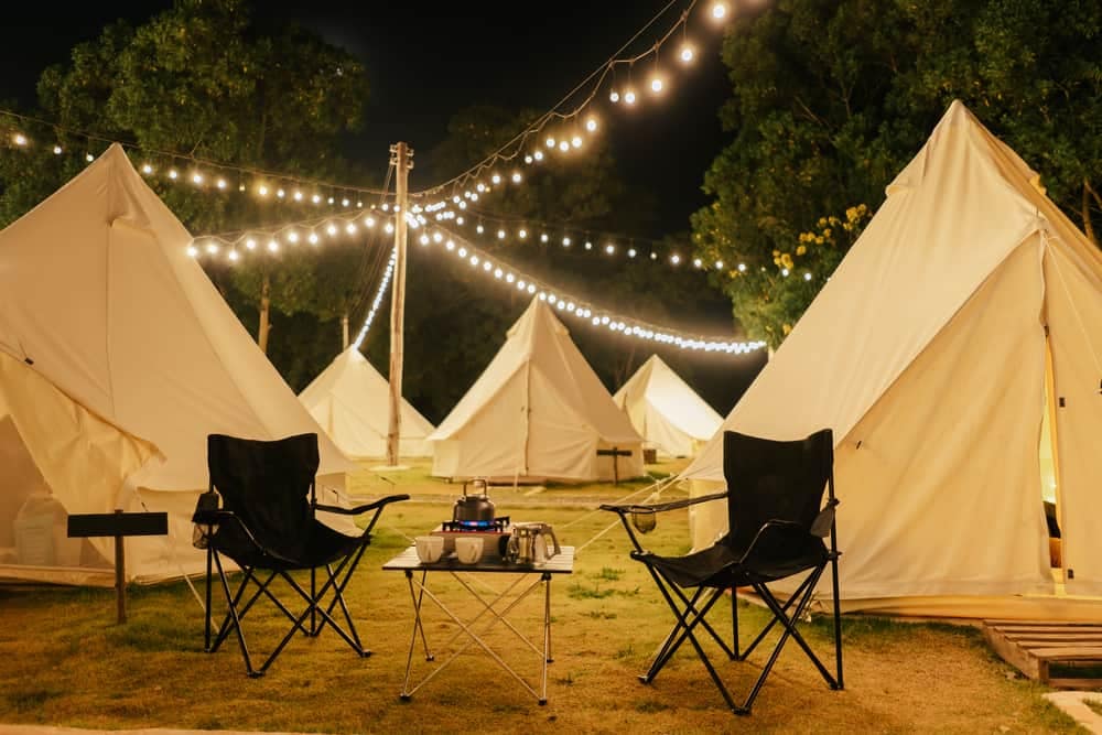 A group of tents set up with chairs and lights in the global glamping market.