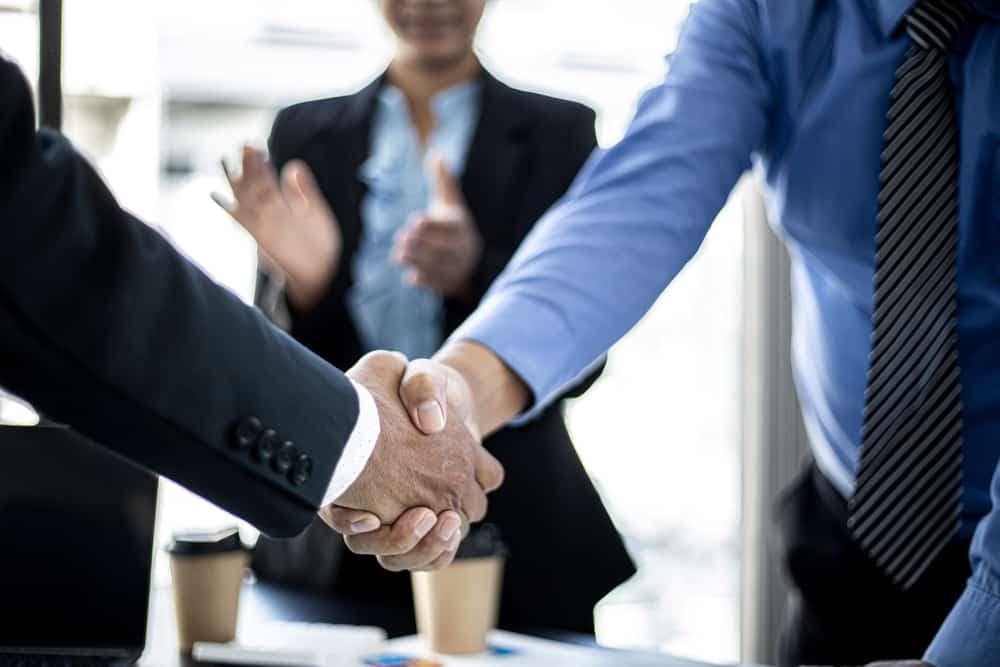 Two business people, one being the General Manager of Lippert, shaking hands in front of a desk.