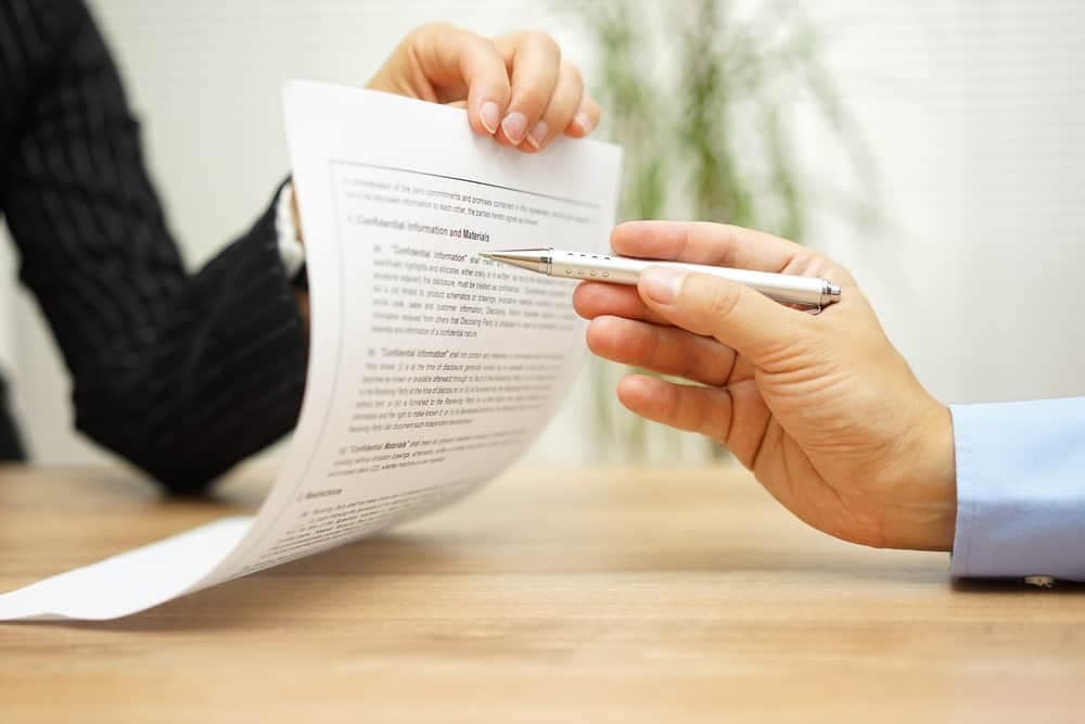 A person signing a document with a pen in order to progress the CRVA's exempting process.