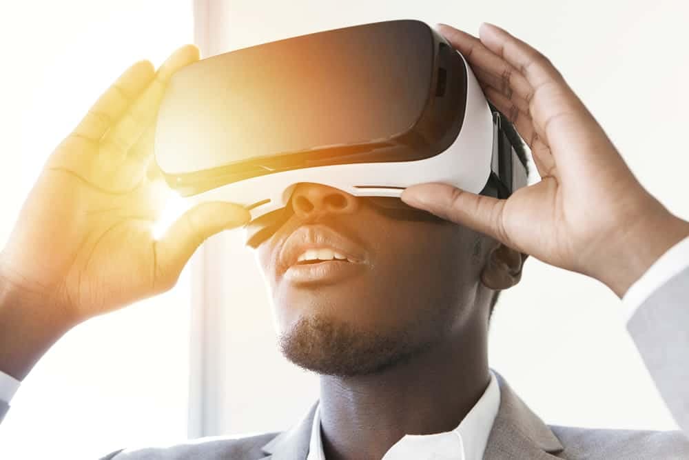 A man wearing a VR headset is immersed in a Virtual Reality Tour, as he gazes at the sun.