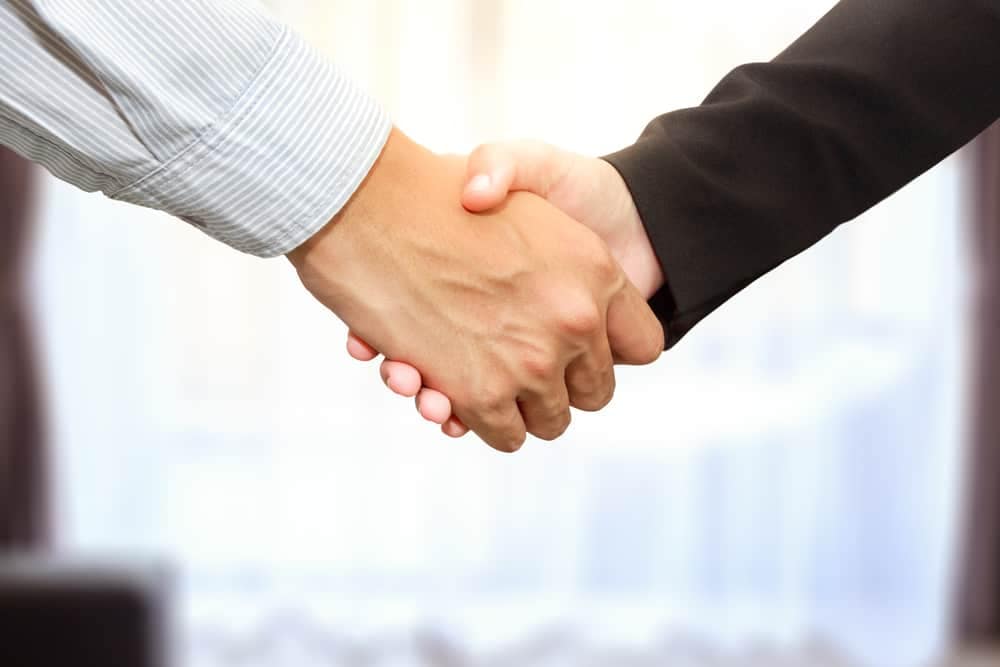 The COO and VP of Operations from Northgate Resorts shake hands in front of a room.