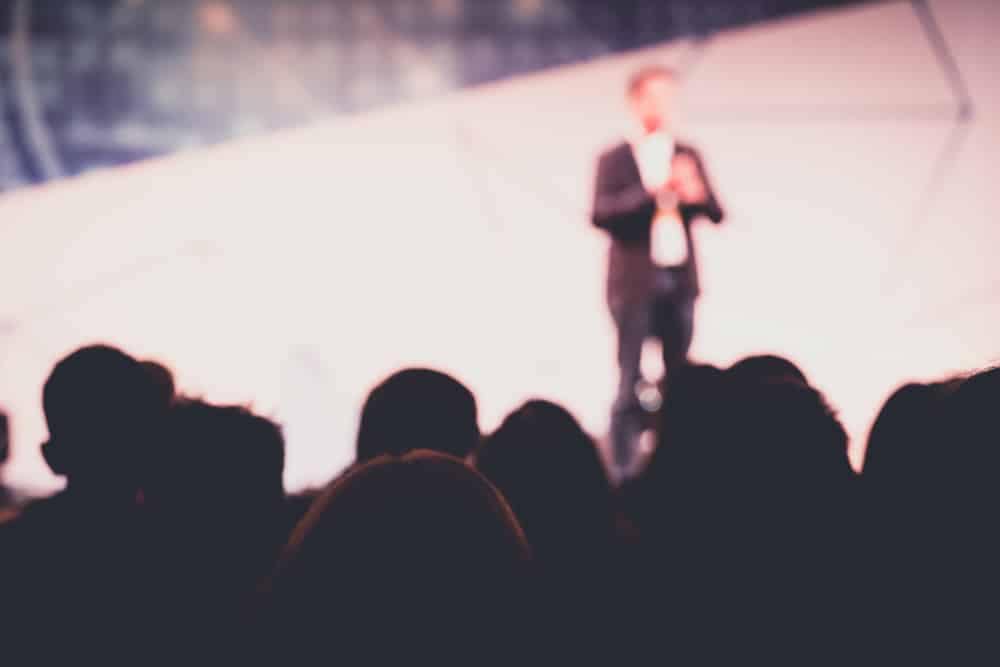 A man is giving a speech on business development and digital marketing strategies at a conference.