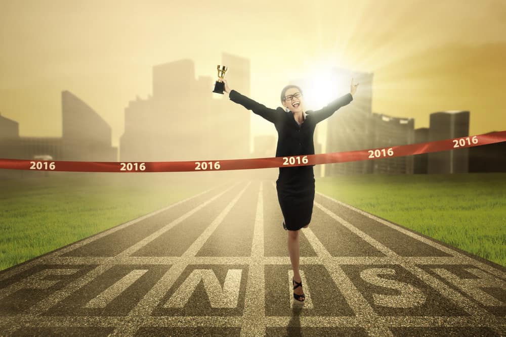 A woman champion in the RV industry crossing a finish line with a trophy.