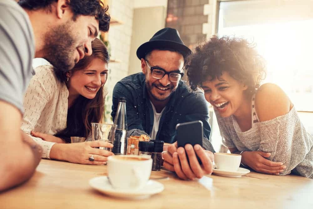A group of friends sitting around a table using the Lippert online 3D Awning Builder on their cell phone.