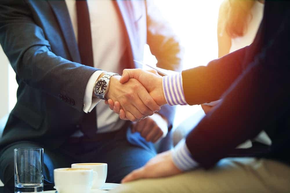 Two business people shaking hands at a meeting discussing Investor Relations.