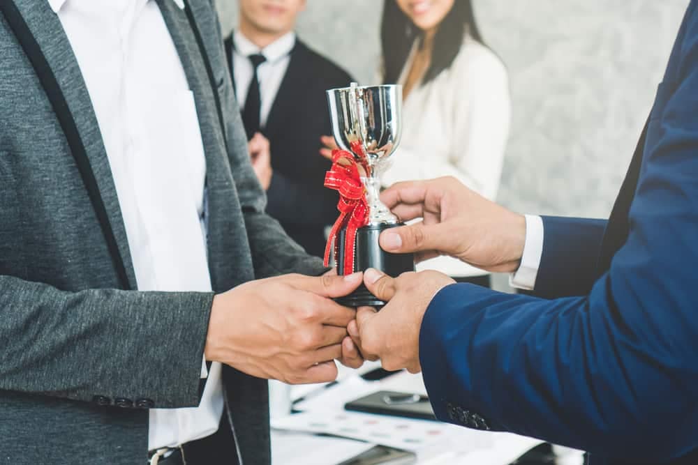 A businessman is handing a trophy to an RV Pro employee.