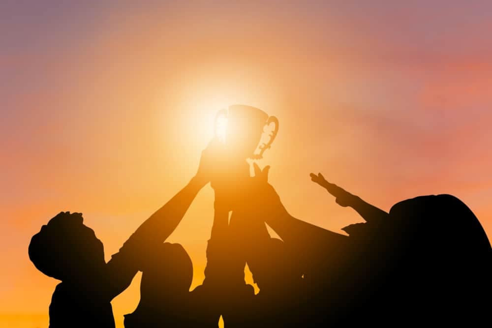 Silhouette of a group of people holding up a trophy at sunset in New South Wales.