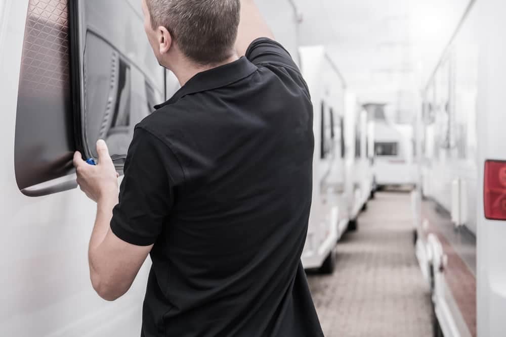 A man fixing the window of a Winnebago RV at an ATG Facility.