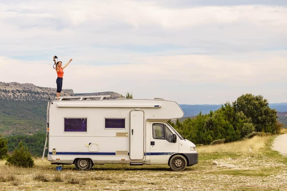 A woman is standing on top of an RV, providing an outdoor hospitality experience for campers.