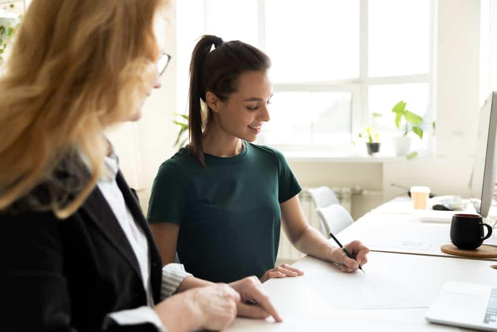 Two women, possibly pilots, sitting at a desk and talking to each other.