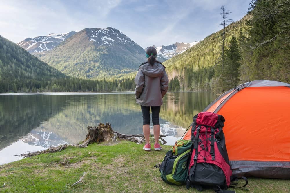 A woman is standing next to a tent near a KOA campground.