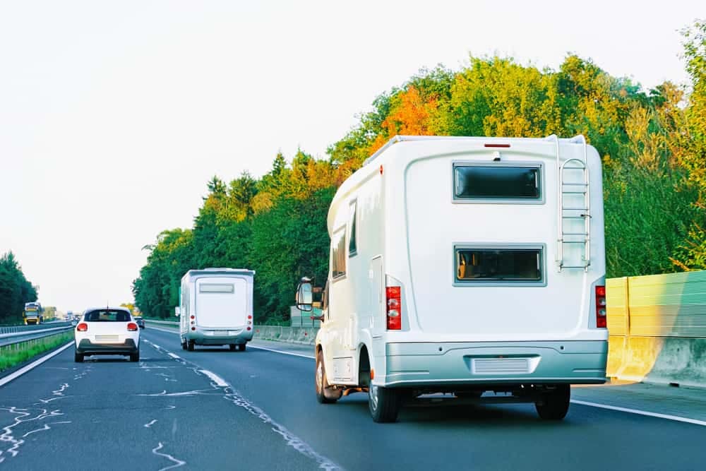 Two RVs on a highway, utilizing a mobile app for their travel planning.