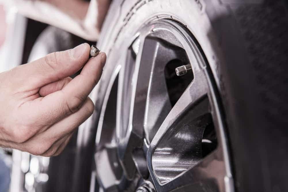 A man fixing a faulty tire on a car.