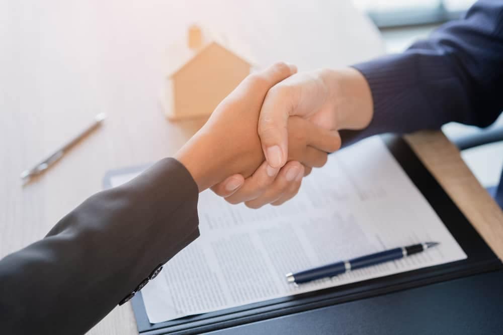 Two business people shaking hands at a desk in Basecamp Resorts.