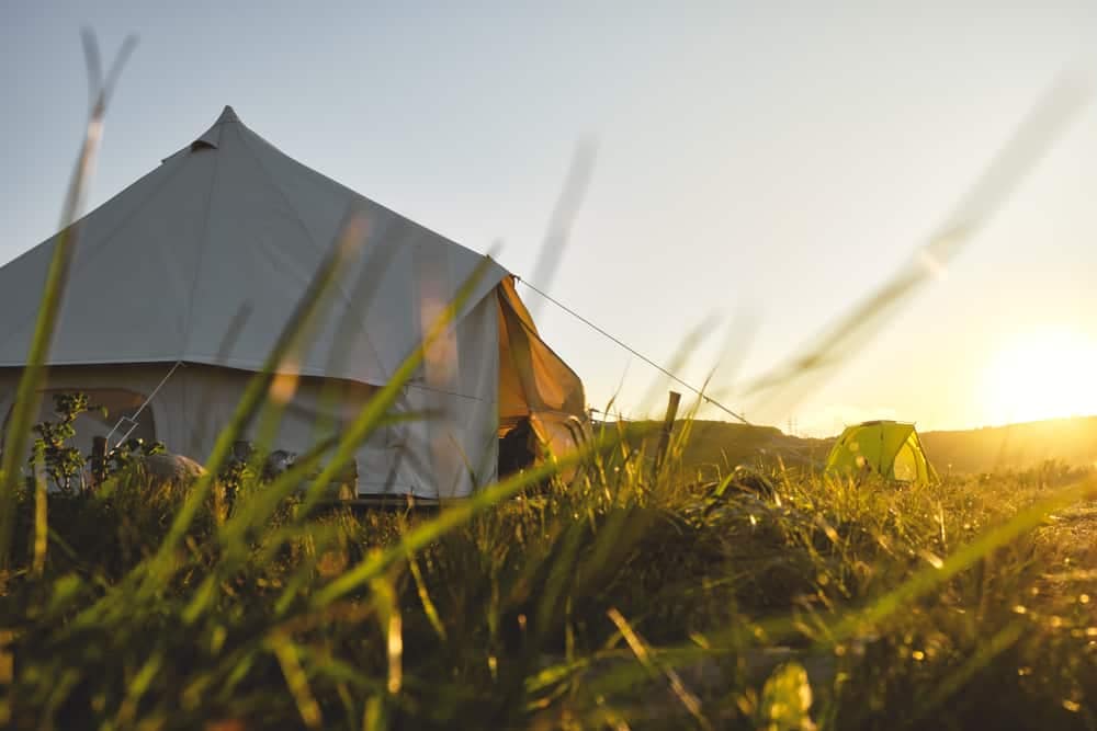 A glamping tent in the grass with the sun setting behind it in Texas.