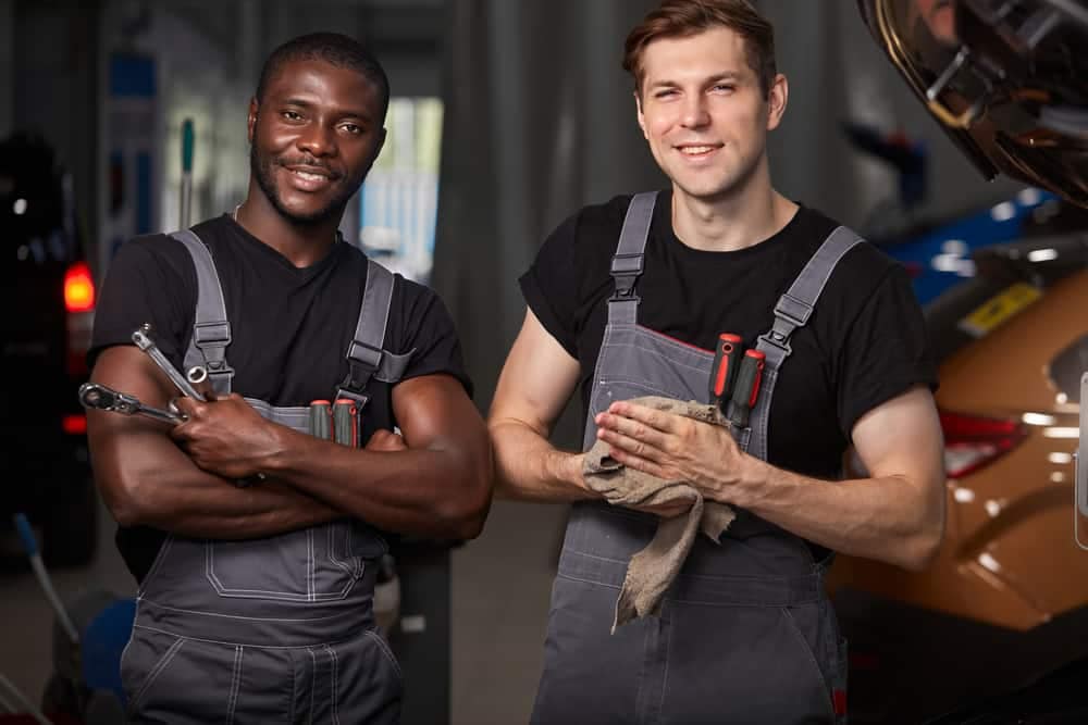 Two mechanics standing in front of a General RV car.