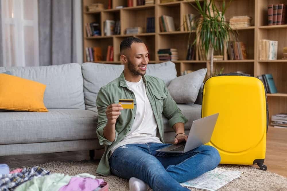 A man sitting on the floor with a laptop and a credit card exploring the RoverPass integration.
