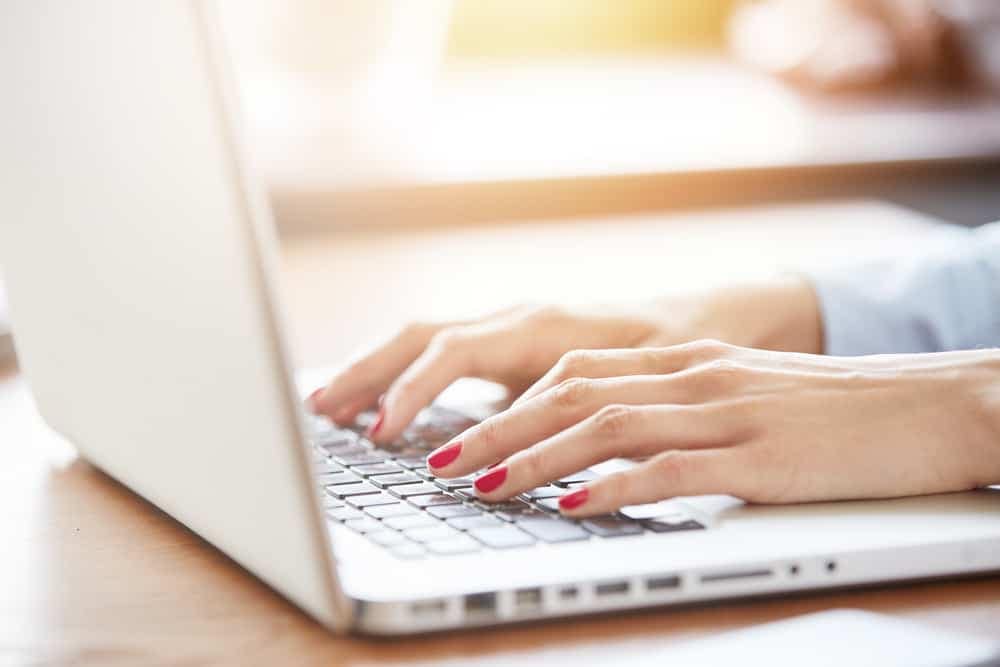 A woman successfully integrating Vrbo and RoverPass by typing on a laptop computer.
