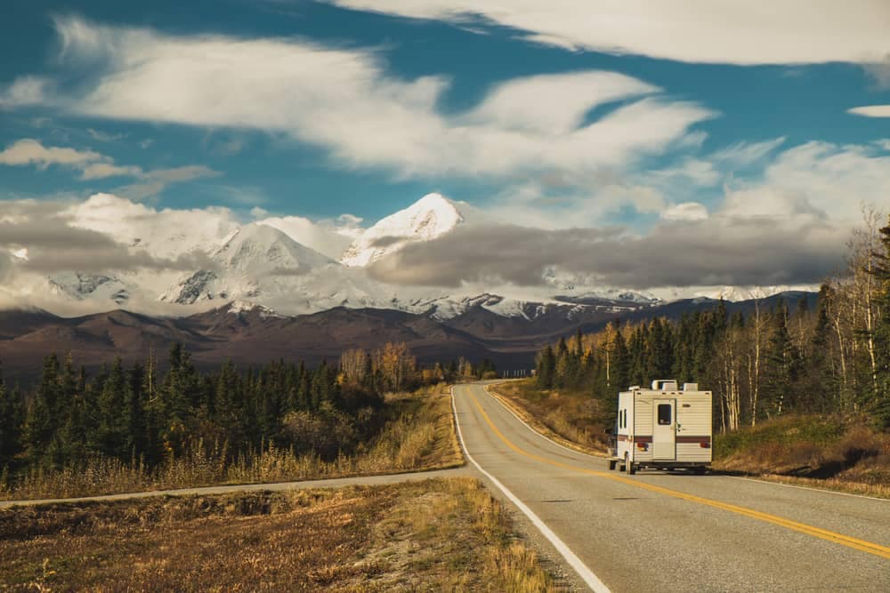 RVers enjoying the picturesque views of mountains as they travel down a road, referencing the RVshare quarterly guide.