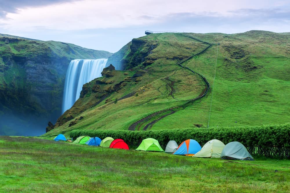 A group of LeadingCampings tents set up in front of a waterfall.