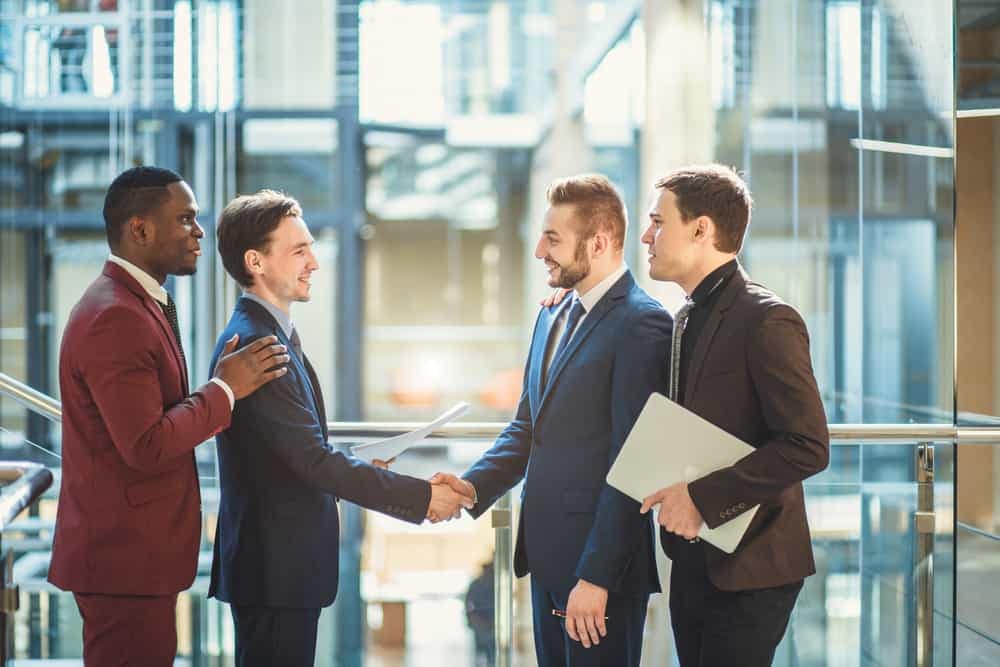 A group of business people from Delaware North shaking hands in an office, discussing the expanding partnership with Grand Canyon Squire Inn.
