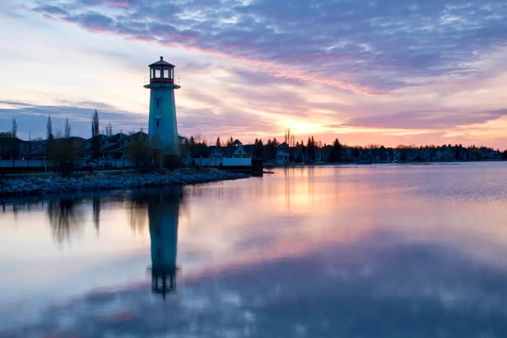 The Sylvan Lake sunset beautifully reflects the lighthouse, creating a picturesque scene.