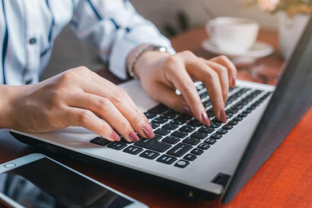A woman's hands effortlessly typing on a laptop keyboard, experiencing unmatched convenience while searching for instant answers at Verde Ranch RV Resort.
