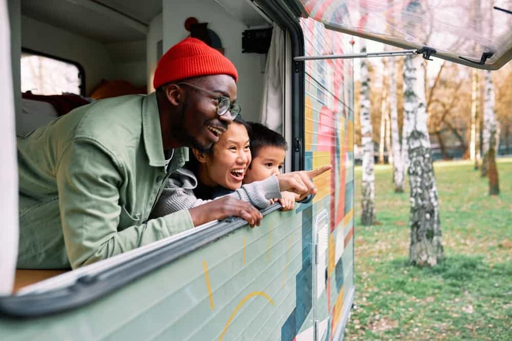 A family of three, including a man and two children, enjoying the view from the window of their camper van during the RV Show in Kitchener.
