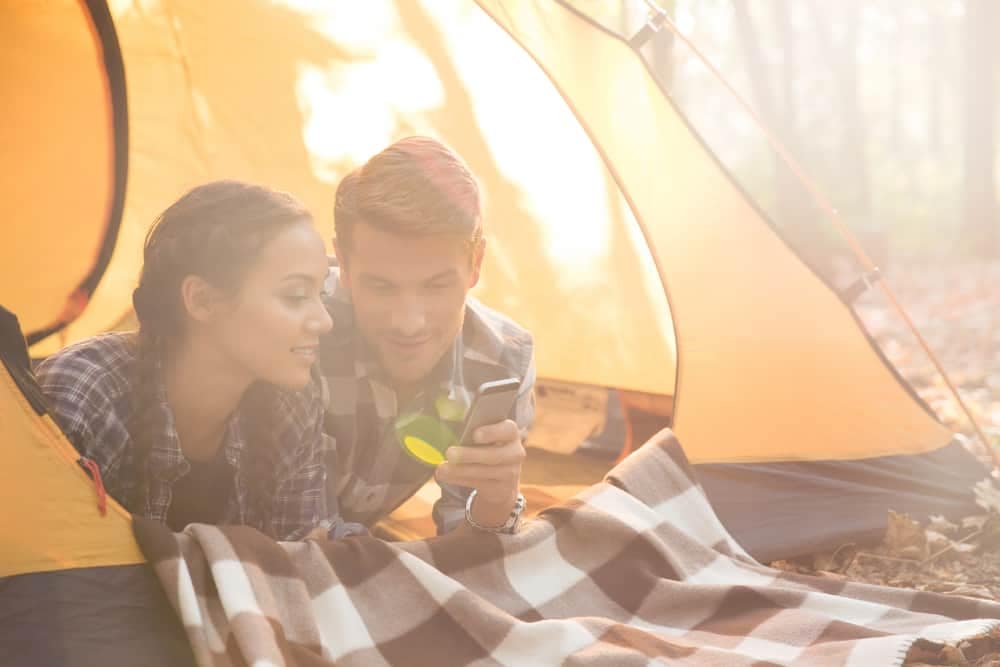 Campers in a tent using their phone.