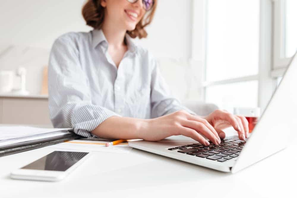 A woman working on a laptop at her desk, experiencing unmatched convenience with an AI chatbot providing instant answers.