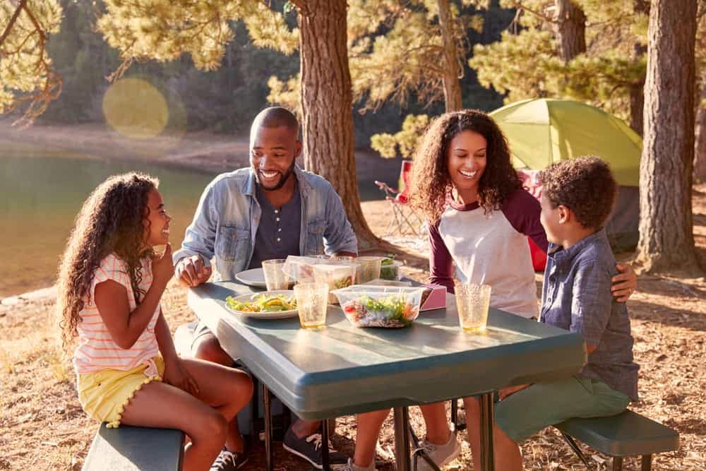A family enjoys a picnic at a KOA campground during camping season.