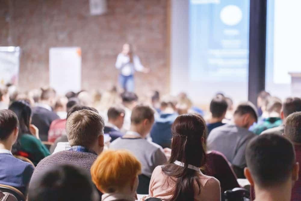 A conference of skilled trades professionals in the RV industry, held at an auditorium, where attendees are watching a presentation organized by the Washington School Counselor Association.