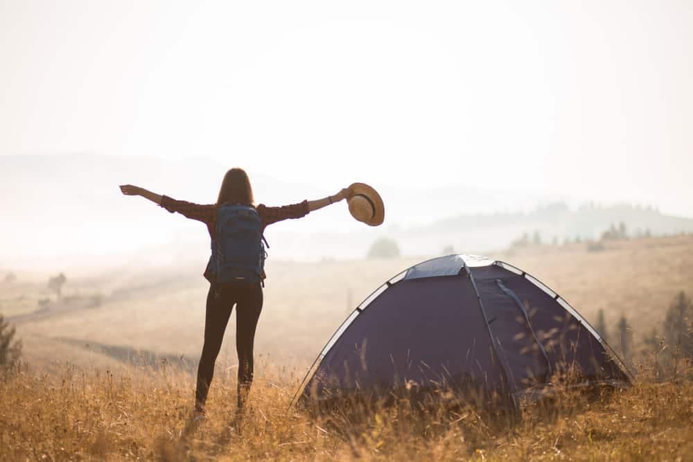 A woman expands her reach with arms outstretched in a field.