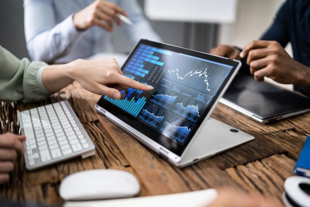 A Financial Analyst team from IVEE Group gathered around a table with a laptop on it.