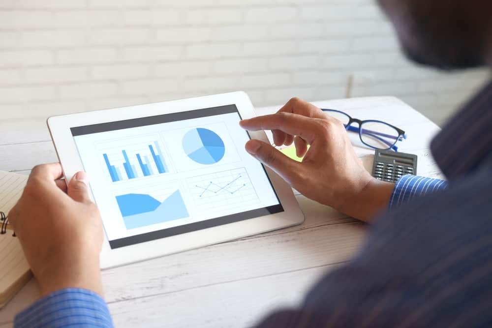 A Financial Analyst from the IVEE Group is using a tablet with graphs.