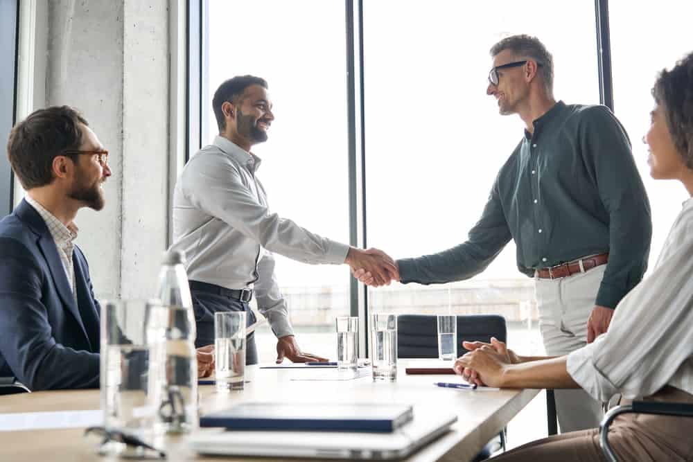 A group of business people shaking hands at a meeting to finalize an acquisition between Camping World and Carbon Emery RV.