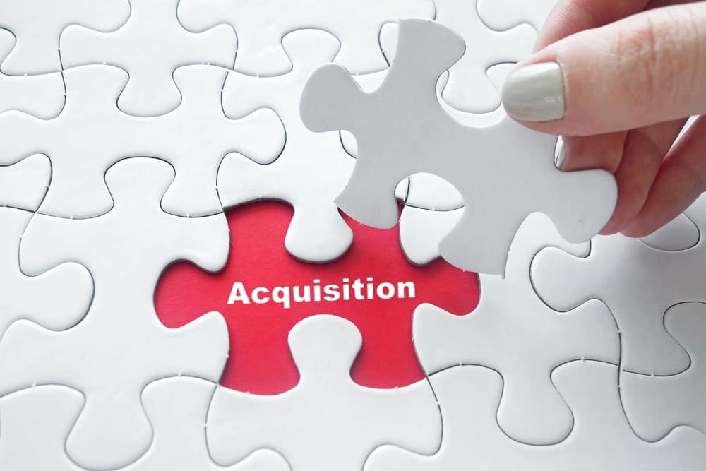 A person placing a piece of a puzzle with the word acquisition at Copper Court RV Park, owned by CMG Parks in Montana.