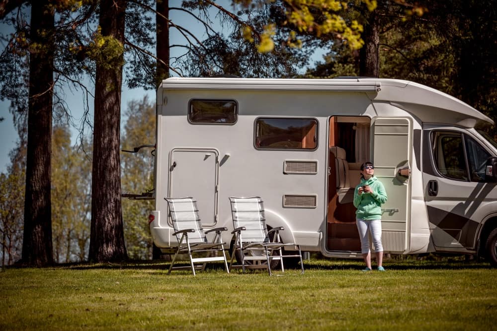 A woman standing next to an RV in the woods, showcasing Sun Communities' Q1 2023 results that exceeded expectations.