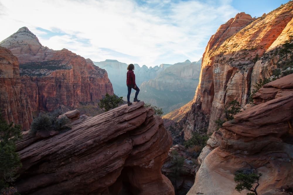 A program director standing atop a cliff in Zion National Park, supporting the outdoor rec industry.